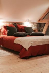 ein Schlafzimmer mit einem großen Bett mit roter Bettwäsche und Kissen in der Unterkunft Duplex accès jacuzzi illimité in Villedieu-les-Poëles