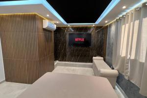 a room with a tv on a wall with a couch at Suíte Gold Cinema 303 in Santo Antônio do Descoberto
