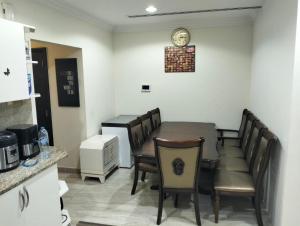 Un comedor con una mesa y sillas y un reloj. en Khaliq Basera, en Dubái