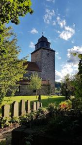 ein Gebäude mit einem Turm in der Mitte eines Feldes in der Unterkunft Ferienwohnung Zum Märchenwald in Hessisch Lichtenau