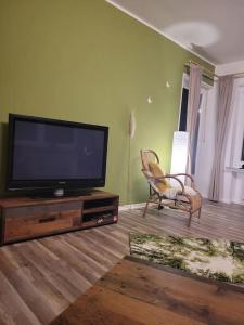 ein Wohnzimmer mit einem Flachbild-TV und einem Stuhl in der Unterkunft Ferienwohnung Zum Märchenwald in Hessisch Lichtenau