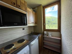 une petite cuisine avec un four micro-ondes et une fenêtre dans l'établissement Résidence Cristallin - Le Cristallin 43 - Agréable 2 pièces offrant une magnifique vue MAE-5184, à Valmorel