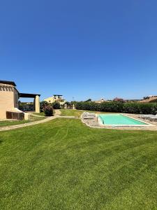 a large yard with a swimming pool and a grass field at Villa Claudia piscina privata in Stintino