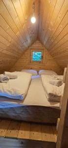 two beds in a wooden cabin with a window at Bungalows Prokletije in Gusinje