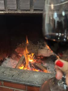 una persona sosteniendo una copa de vino junto al fuego en Camping Sem Cama - Leve sua Barraca, en Chapada dos Guimarães