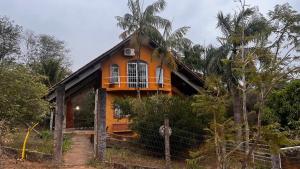 una casa amarilla con una valla delante en Camping Sem Cama - Leve sua Barraca, en Chapada dos Guimarães