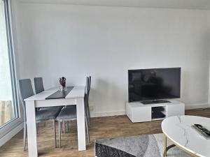 a living room with a white table and a television at Le dix-septième ciel vue sur la tour Eiffel in Épinay-sur-Seine