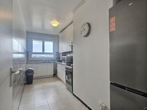 a kitchen with a clock on the wall at Le dix-septième ciel vue sur la tour Eiffel in Épinay-sur-Seine +13 photos