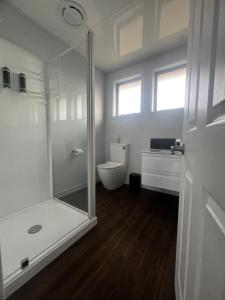 a white bathroom with a shower and a toilet at ASURE Surrey Court Motel Invercargill in Invercargill +8 photos
