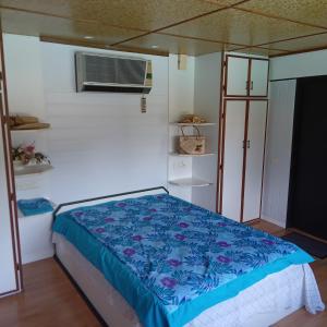 une chambre avec un lit recouvert d'une couette bleue dans l'établissement Fare MIHIMANA, à Paea