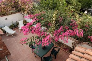 a patio with pink flowers and a table and chairs at La campagna e il mare in Catania