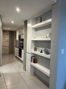 a living room with white shelves and a kitchen at Lichen Haven Suite in Windhoek