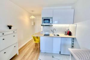 a kitchen with white cabinets and a yellow chair at Super studio Paris La Défense in Courbevoie