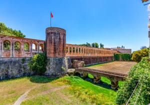 ピサにあるCasa sulle Mura Anticheの野原にある橋のある古いレンガ造りの建物