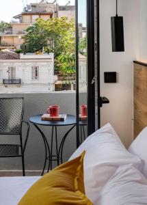 a bed and a table with two cups on a balcony at The Meta Stay - Sunny Getaway with Rooftop Access in Athens