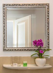 um espelho por cima de um lavatório com um vaso com flores roxas em Hotel Storchen em Ravensburg