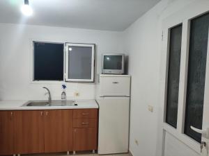a kitchen with a sink and a refrigerator and a tv at Relaxhouse in Himare