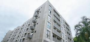 a tall gray building with windows and a palm tree at Option Full Service Residence in Rio de Janeiro