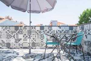 een terras met twee stoelen en een parasol bij Panoramic luxury apartment w AC Downtown and Metro in Porto
