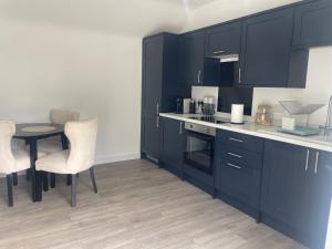 a kitchen with black cabinets and a table and chairs at The Old Stable, Rustic Charm Modern Comforts in Gorfield