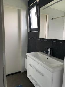 a bathroom with a white sink and a mirror at Enkhuizer Strand Chalet Windrose mit Zaun Haus Nr 225 in Enkhuizen
