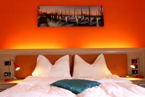 Una cama con almohadas blancas y una pintura encima. en Ely'S Residence en Romano D'Ezzelino