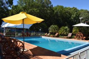 una piscina con ombrellone e sedie gialli di Cabañas Oberá a Oberá