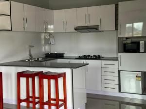 a kitchen with white cabinets and red bar stools at Prasad Apartments in Labasa