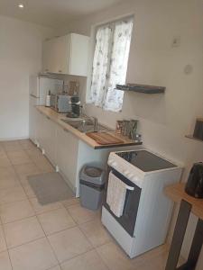a small kitchen with a sink and a stove at maison 2 chambres 4 lits 15mn Aéroport de Beauvais 5mn du château de la trye in Hermes +20 photos