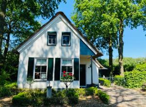 a white house with black shutters and flowers in a yard at Vakantiehuis Villa 56 in Heel