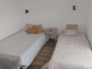 two twin beds in a room with a nightstand and a bedskirts at Casa da Tia Avelina in Angra do Heroísmo