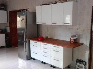 a kitchen with white cabinets and a stainless steel refrigerator at White House in Ziguinchor