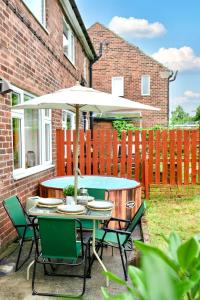 a table and chairs with an umbrella in a yard at A Luxurious Home with Hot Tub and Man Cave! 9ppl in Whiston