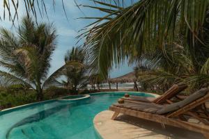 una piscina con 2 tumbonas y palmeras en Cabanas Adobe Frente Al Mar, en Puerto Escondido