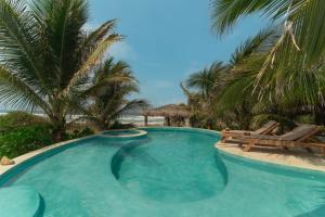 een zwembad met 2 stoelen en palmbomen bij Cabanas Adobe Frente Al Mar in Puerto Escondido