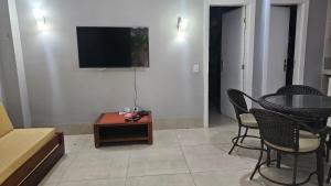 a living room with a table and a tv on a wall at Hotel Luupi Esmeralda Apto 159 - Rio Quente GO in Rio Quente