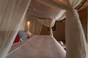Una cama con cortinas blancas en un dormitorio. en Cabanas Adobe Frente Al Mar, en Puerto Escondido