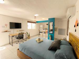 a bedroom with a large bed and a desk at Comfy studio Yaxkin on downtown, 3 block away from sea and sunsets in Cozumel