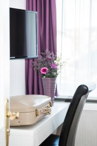 a suitcase sitting on a table with a tv and flowers at Hotel Storchen in Ravensburg