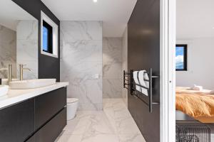 a bathroom with a sink and a toilet and a bed at Anaka in Wanaka +23 photos