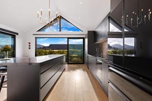 a kitchen with black cabinets and large windows at Anaka in Wanaka
