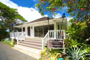 una piccola casa bianca con un cartello davanti di Kiahuna Plantation and Beach Bungalows by Castle a Koloa