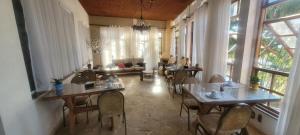 a dining room with tables and chairs and windows at Pousada Aconchego de Minas in Juiz de Fora