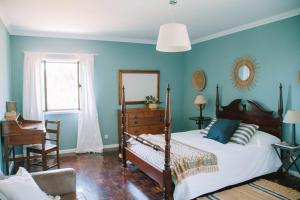 a bedroom with a bed and a chair and a mirror at Just Like Home - Casa de Cimo de Vila in Vila Nova de Cerveira