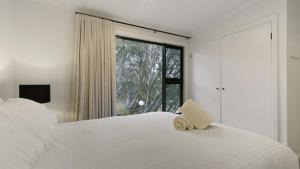 a bedroom with a white bed with a window at Higgi Drive 6 in Mount Hotham