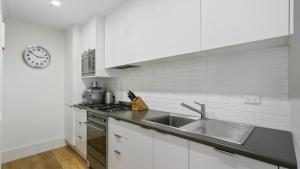 a white kitchen with a sink and a stove at Shamrock 1 in Mount Hotham +3 photos