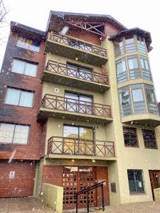 un edificio alto de ladrillo con nieve cayendo sobre él en Departamento Céntrico Belgrano 2, en San Carlos de Bariloche