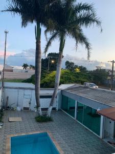 a house with a swimming pool and two palm trees at Casa Branca in Londrina