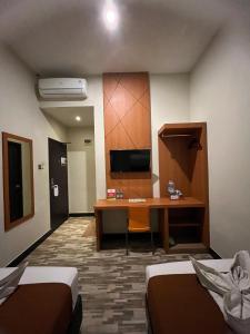 a room with a desk and a room with two beds at Bless Hotels in Sintang