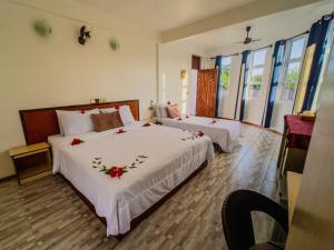 a bedroom with two beds with red flowers on them at Hanifaru Beach Inn in Baa Atoll